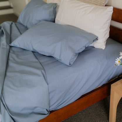 Bed with blue linen showing duvet folded back and matched sheet with pillow