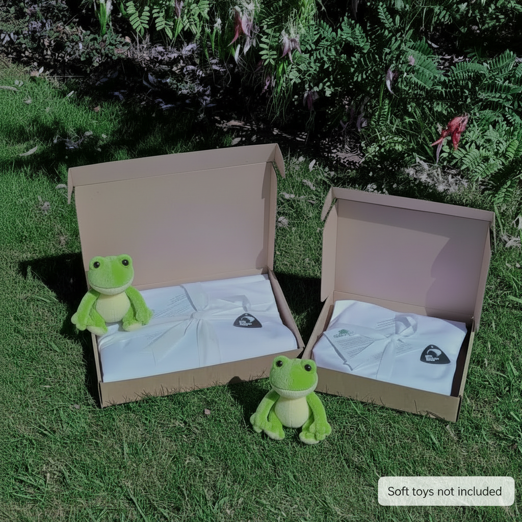 cot sheet sets in giftbox - sitting in natural garden, featuring 2 green frog toys ( not included with products) 