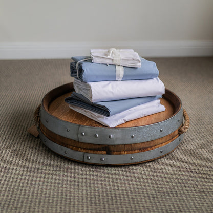 Stack of folded SleepFROG pillowcases and sheets on  oak barrel lid. 
