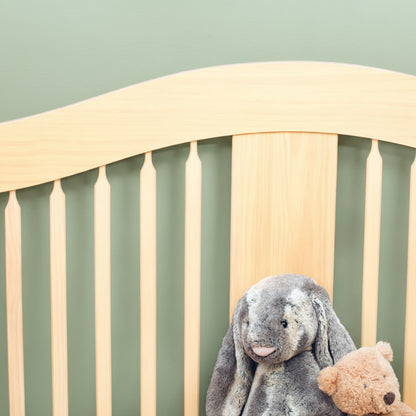 Wooden cot  with stuffed animals against a soft green wall